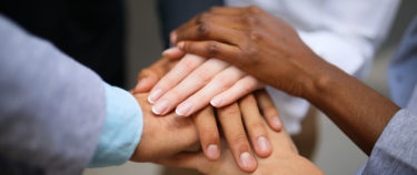Business people joining hands in a huddle. Close up.