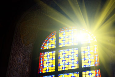 Beautiful stained glass window with sunlight. Religion and art concept.