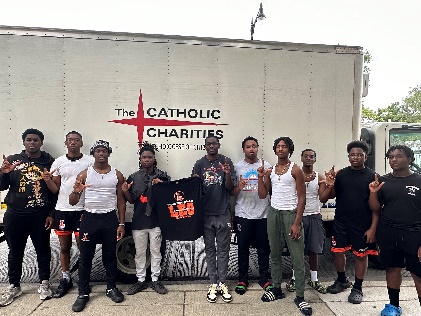 Group of people posing for camera in front of Catholic Charities truck