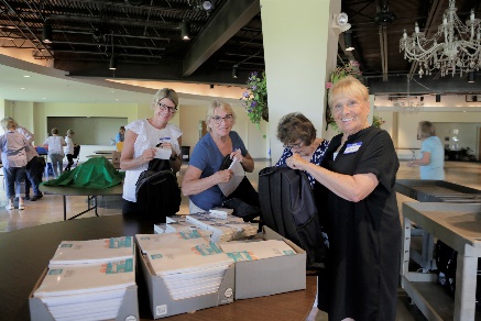 People smiling and assembling backpacks