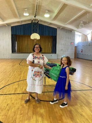 Two people with dresses standing and smiling in a gymnasium