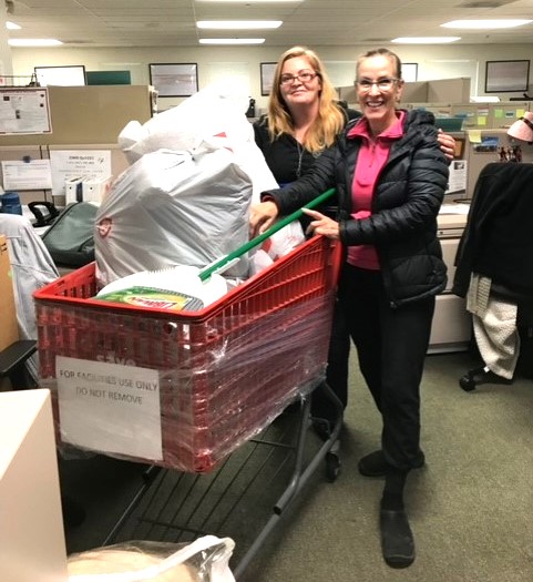Two people smiling with shopping cart full of donated goods.