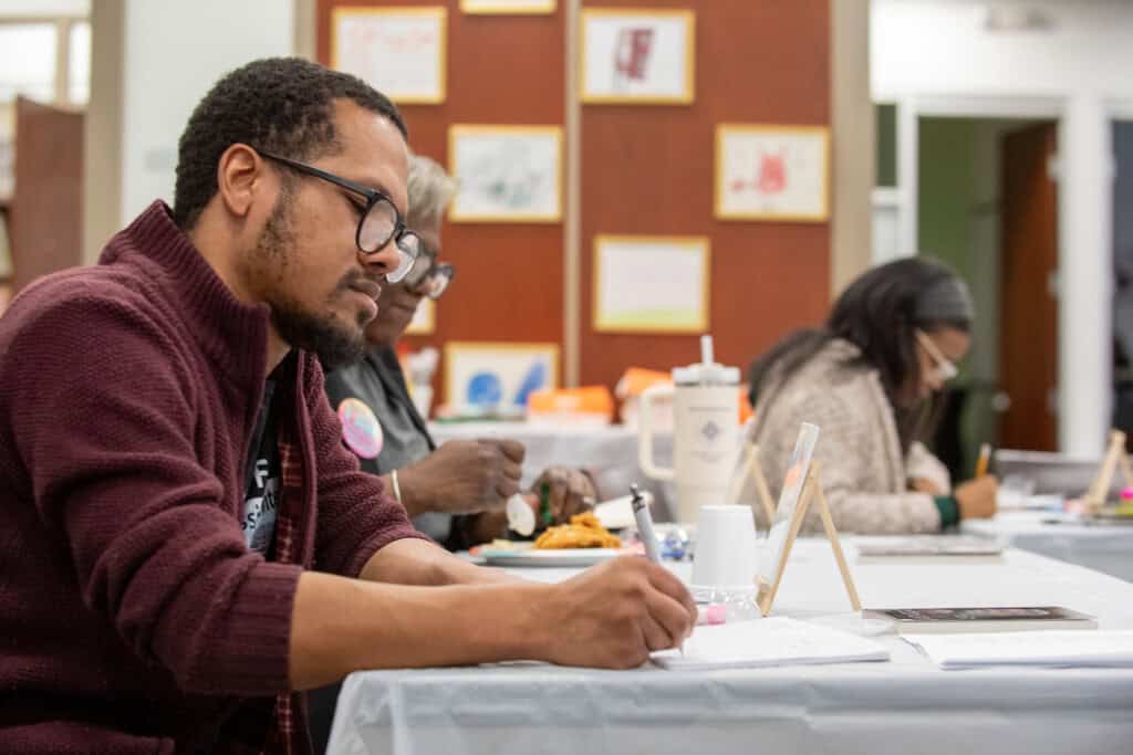 People creating art and writing poems at Poetry reading and art expression class