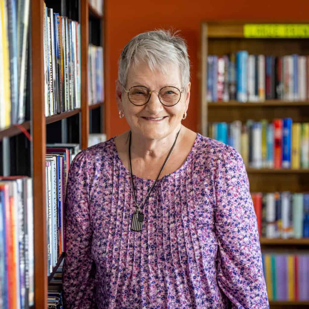 Senior smiling in front of a bookshelf at an Assisted Living facility