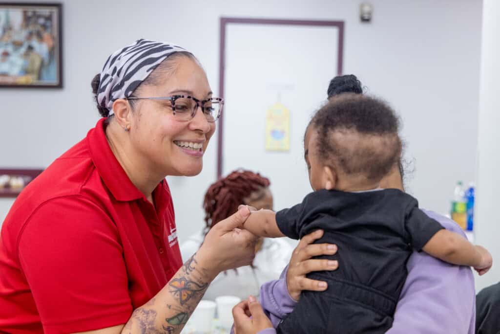 Doula manager Nicole Harper-Spencer greets 16-year-old Tyreanna Sweatt who holds her newborn son Tyrell,
