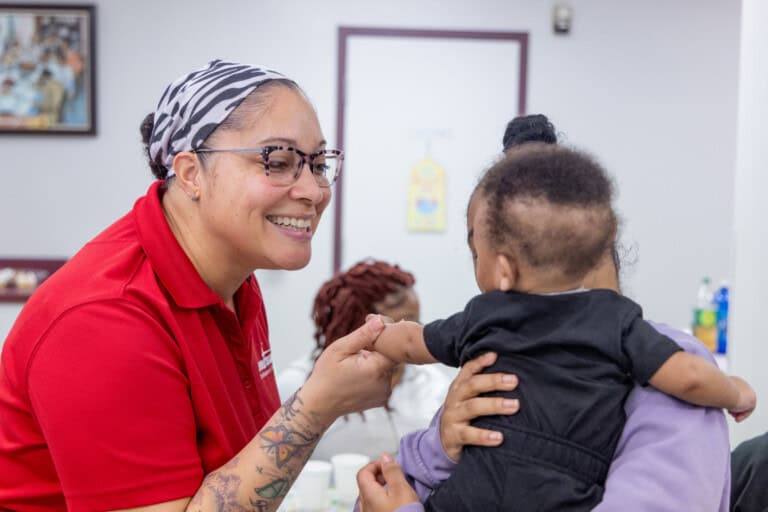 Doula manager Nicole Harper-Spencer greets 16-year-old Tyreanna Sweatt who holds her newborn son Tyrell,
