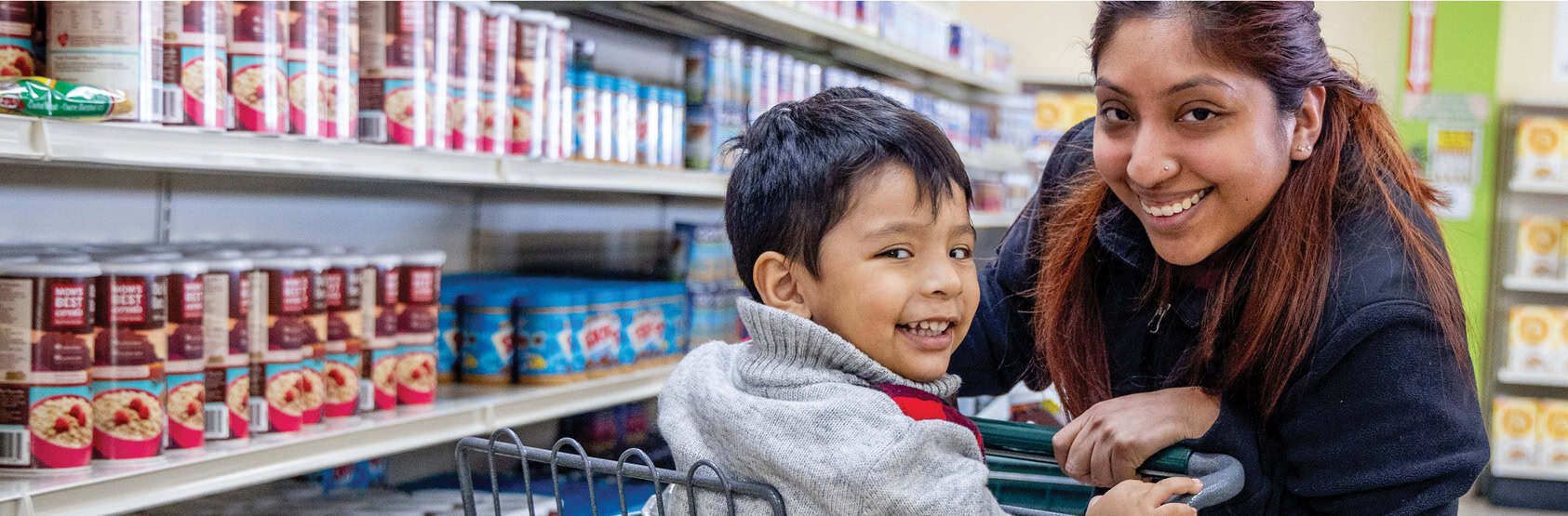 Woman smiling with her son in a grocery cart