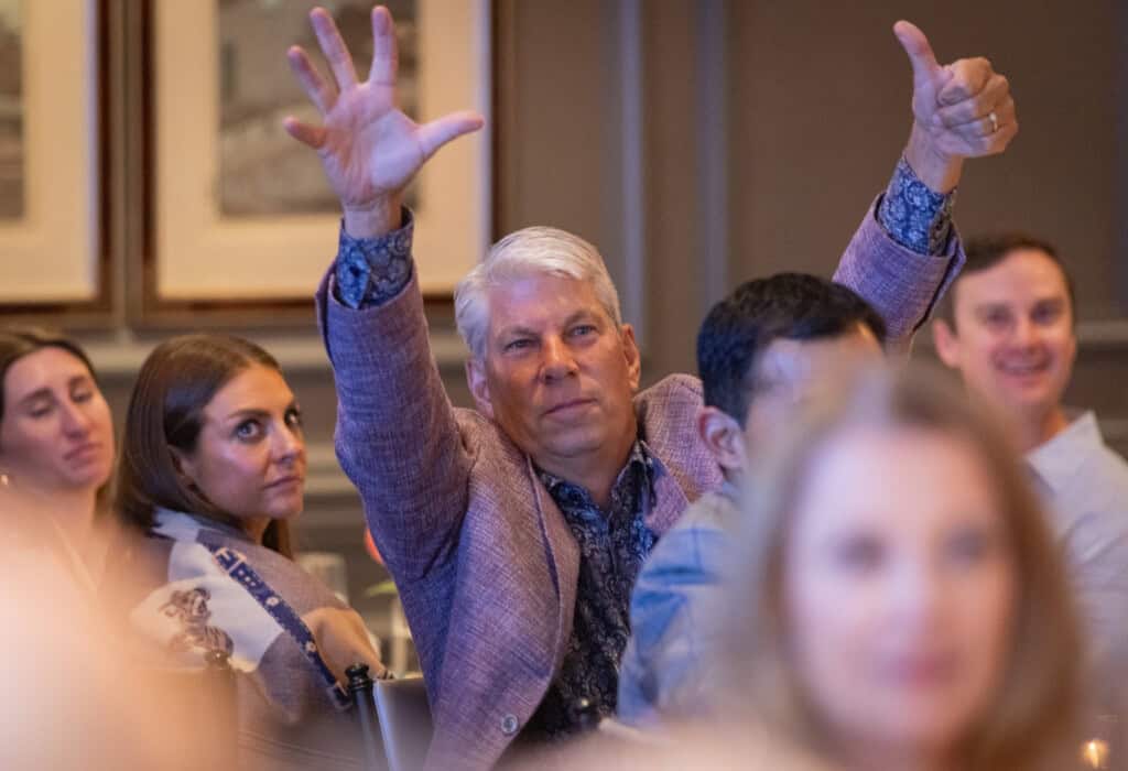 Man holding up 6 fingers at Art of Caring Fundraiser