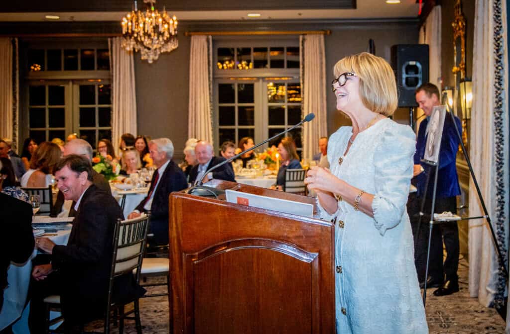 Woman giving speech at Art of Caring fundraiser