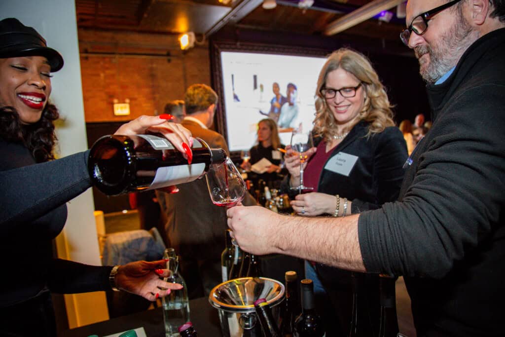 Woman pouring wine for guests of 2026 D'Vine Affair